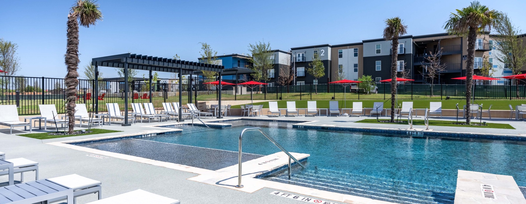 Sparkling pool with lounge seating and apartment buildings in the background